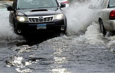 Cars drive through flooding